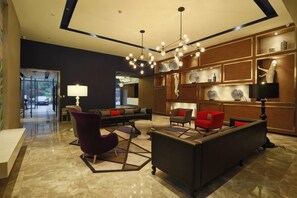Eine moderne Lobby mit einer Couch, Sesseln, einem Couchtisch und einem Kronleuchter.