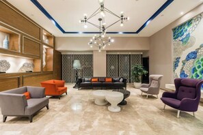 A modern lobby with a chandelier, seating area, and decorative wall art. - Orange Hotel (Wuxi Oufeng Street Huishan Ancient Town Branch) (Wuxi)