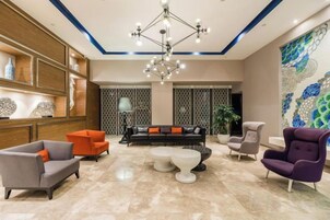 A modern lobby with a chandelier, seating area, and decorative wall art.