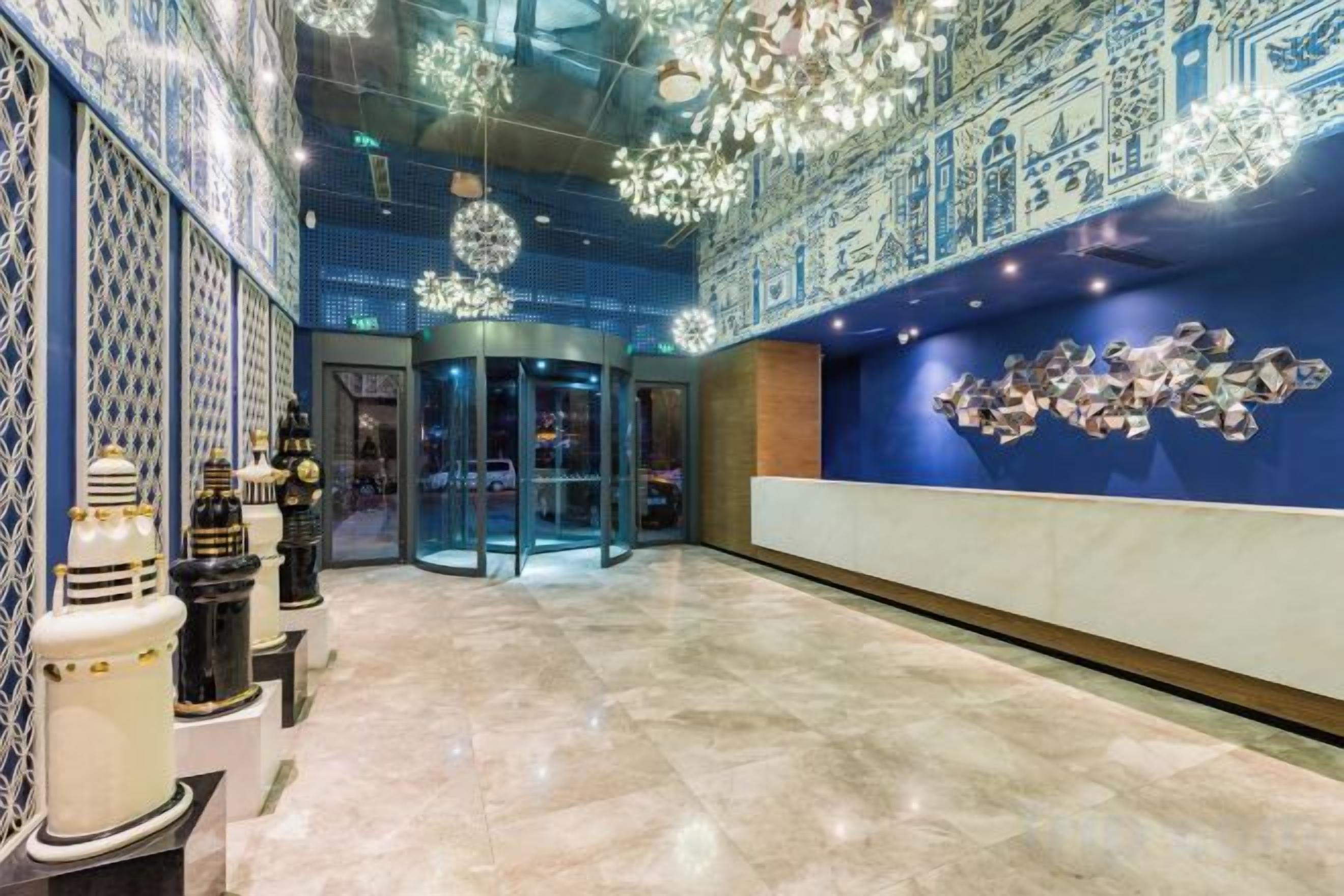 A lobby with a marble floor, a revolving door, and a wall with a decorative pattern.