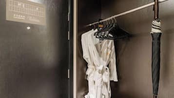 A wooden door with a sign, a white robe hanging on a rack, and a striped umbrella on a hook.