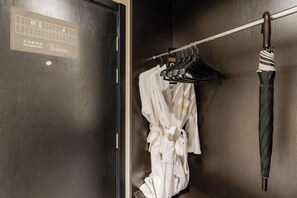 Une porte en bois avec une pancarte, une robe blanche suspendue à un porte-manteau et un parapluie à rayures accroché à un crochet.