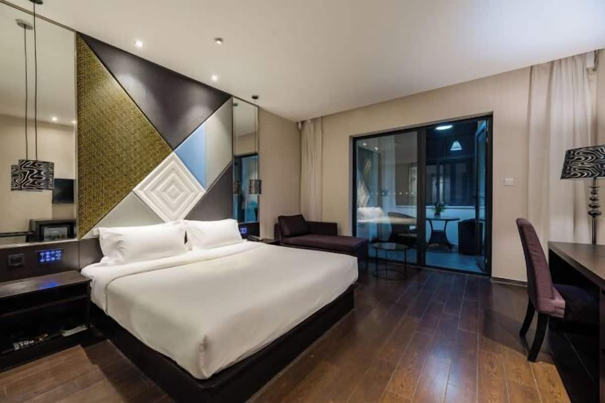 A modern hotel room with a large bed, a desk, and a seating area.