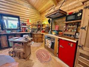 Prepare meals in this cabin-style kitchen with a sink, stove, and ample counter space.