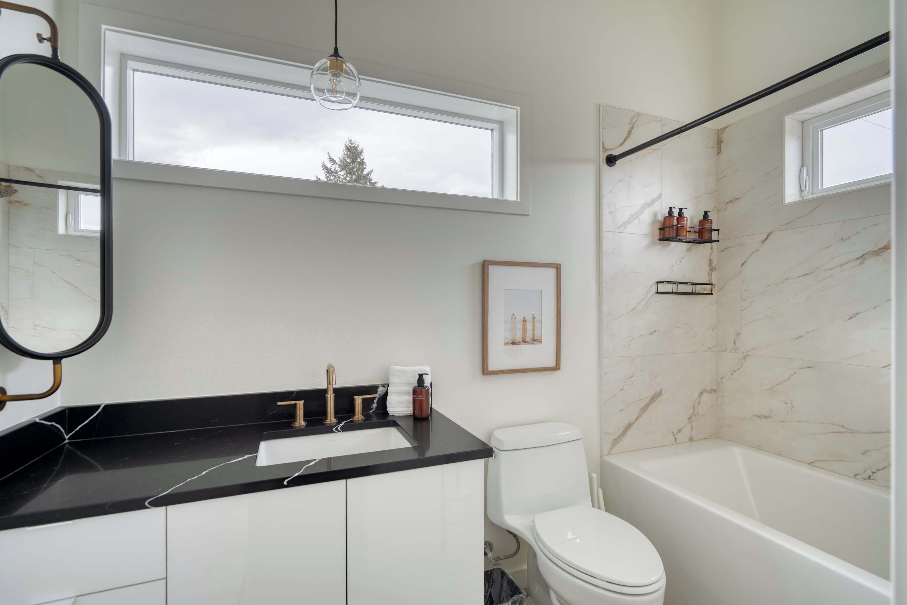 Une salle de bain moderne avec un plan de toilette noir, des toilettes blanches et une baignoire.