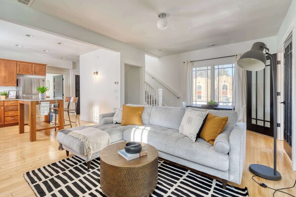 A modern living room with a grey sectional sofa, a round coffee table, and a black and white rug. - 2BR/2BA • Sunny Retreat • Parks + Coffee Nearby (Portland)