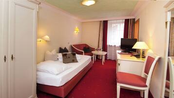 Ein Hotelzimmer mit einem Bett, einem Schreibtisch mit Stuhl, einem Fernseher und einem kleinen Tisch.