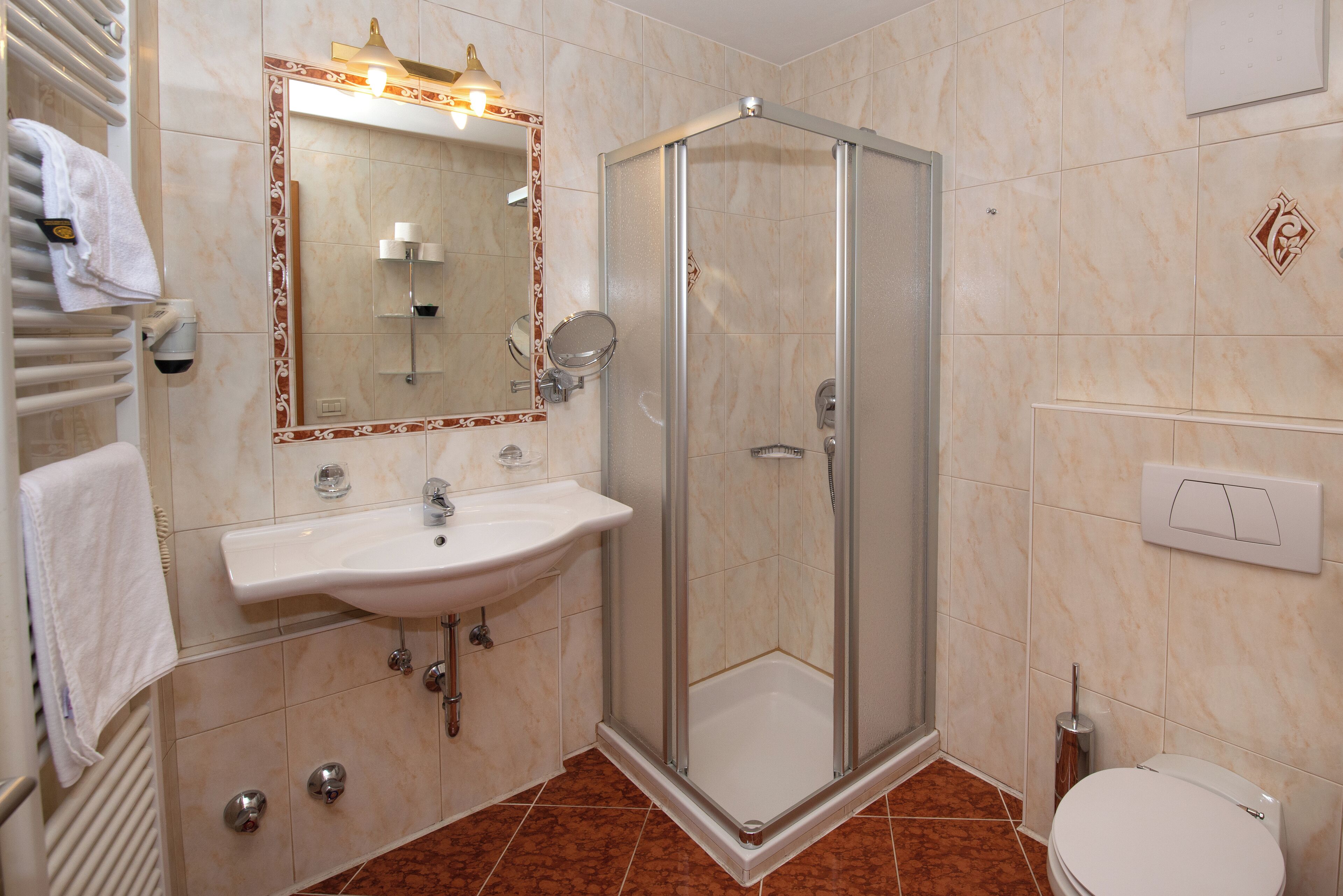 A bathroom with a glass-enclosed shower, a sink with a mirror, and a toilet.