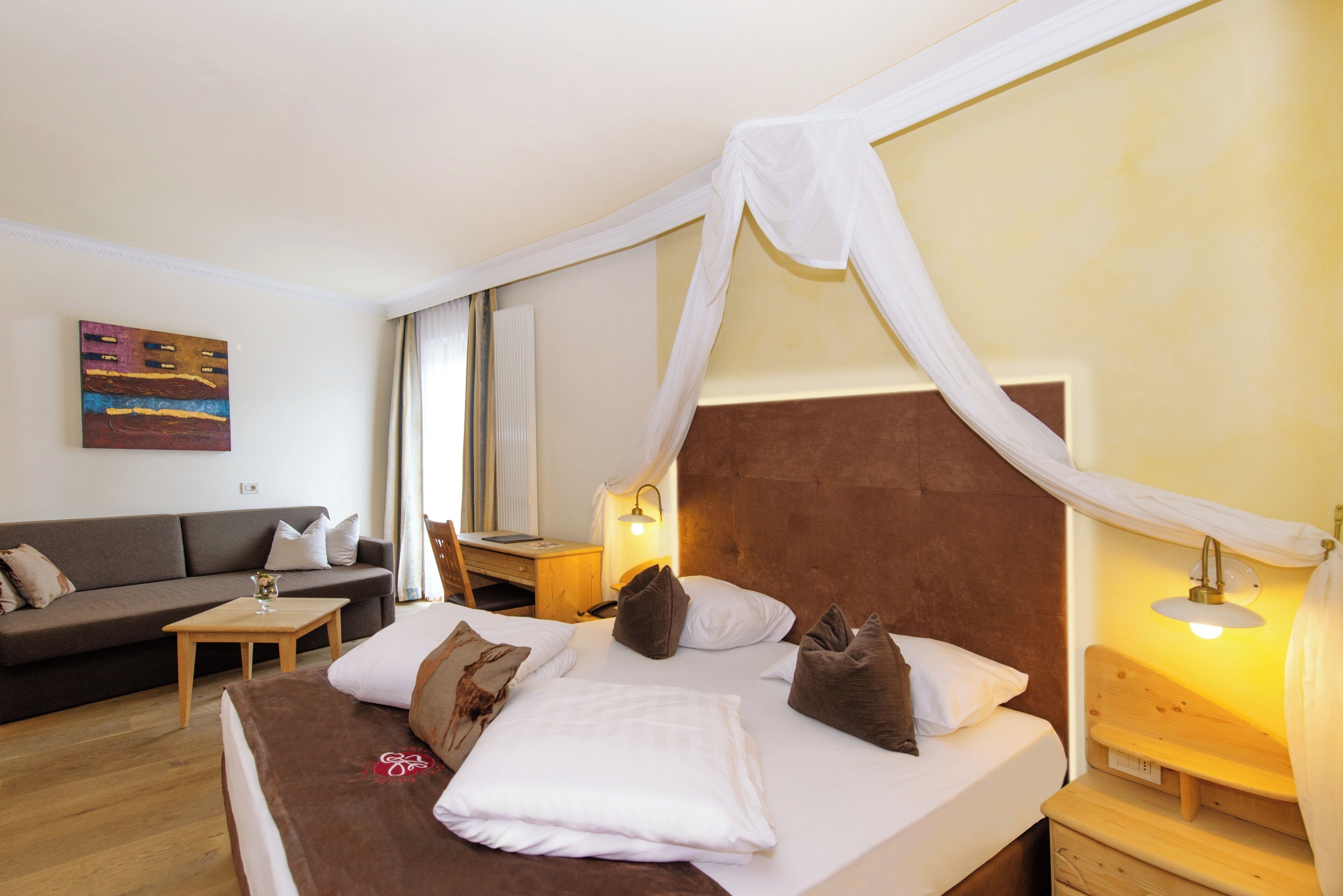 Una habitación de hotel con una cama, un sofá, un escritorio y una lámpara.