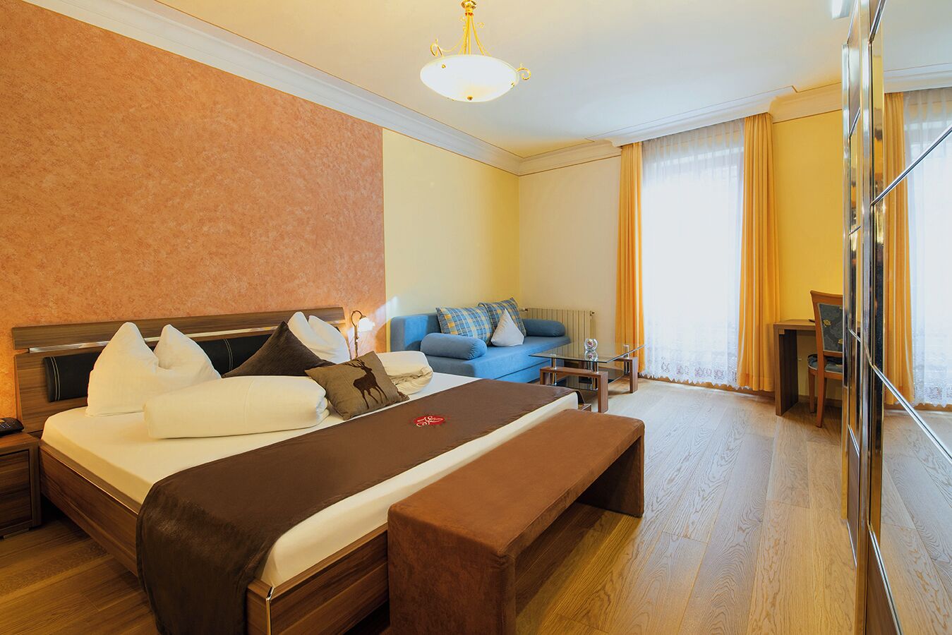 Una habitación de hotel con una cama grande, un sofá, una mesita y un banco.