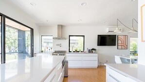 A modern kitchen with white cabinetry, a large island, and a built-in stove.
