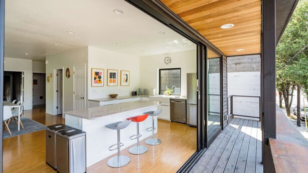 A modern kitchen with a central island, stainless steel appliances, and a wooden ceiling.