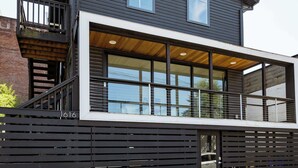 A modern two-story building with a large glass window on the ground floor and a balcony on the upper floor.