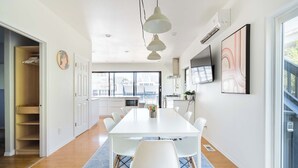 A modern dining area with a white table, white chairs, and pendant lighting.