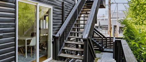 Eine Holzterrasse führt zu einem modernen Haus mit Treppe und Glastür.