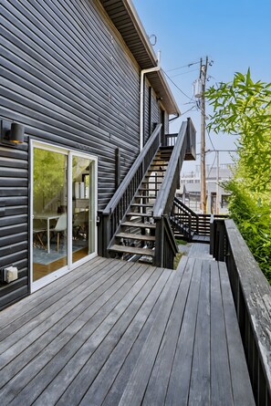 A wooden deck leading to a modern house with a staircase and a glass door entrance. - 4 Queen Bedrooms, Walk to the Pearl and NW 23rd (Portland)