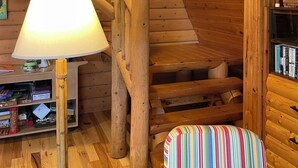 A wooden staircase with a lamp and a colorful cushion in a cabin-style room. - Updated 3 bedroom A-Frame CABIN on the Fox River in Princeton with WiFi, AC (Princeton)