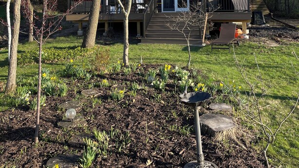 A log cabin with a deck, surrounded by trees and a garden with stepping stones. - Updated 3 bedroom A-Frame CABIN on the Fox River in Princeton with WiFi, AC (Princeton)