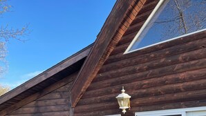 A wooden cabin with a deck, a white Adirondack chair, and a large sliding glass door. - Updated 3 bedroom A-Frame CABIN on the Fox River in Princeton with WiFi, AC (Princeton)