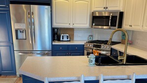A kitchen with a central island, stainless steel appliances, and white cabinetry. - Updated 3 bedroom A-Frame CABIN on the Fox River in Princeton with WiFi, AC (Princeton)