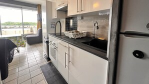 A compact kitchen with white cabinets, a black countertop, and a stainless steel sink.