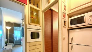 A kitchen with a built-in oven, a microwave, and a refrigerator.
