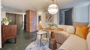 A modern living room with a round coffee table, a sofa, and a brick accent wall. - Renovated 2BR Garden Suite • Steps to NW 23rd (Portland)