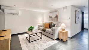 A modern living room with a sofa, coffee table, and side table, featuring artwork and a plant. - Renovated 2BR Garden Suite • Steps to NW 23rd (Portland)