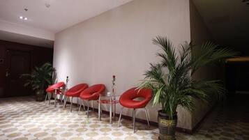 A lobby with a patterned floor, a reception desk, and red chairs.