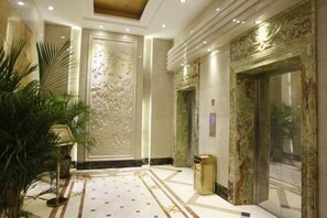 Un lobby lujoso con piso de mármol, paneles decorativos en las paredes y un moderno ascensor.