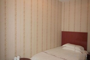 A single bed with a wooden headboard in a room with striped wallpaper. - Zhaoyuan Wenfeng Hotel (Zhaoyuan)