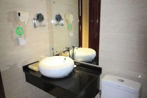 A bathroom with a white sink, a black countertop, a mirror, and a toilet. - Zhaoyuan Wenfeng Hotel (Zhaoyuan)