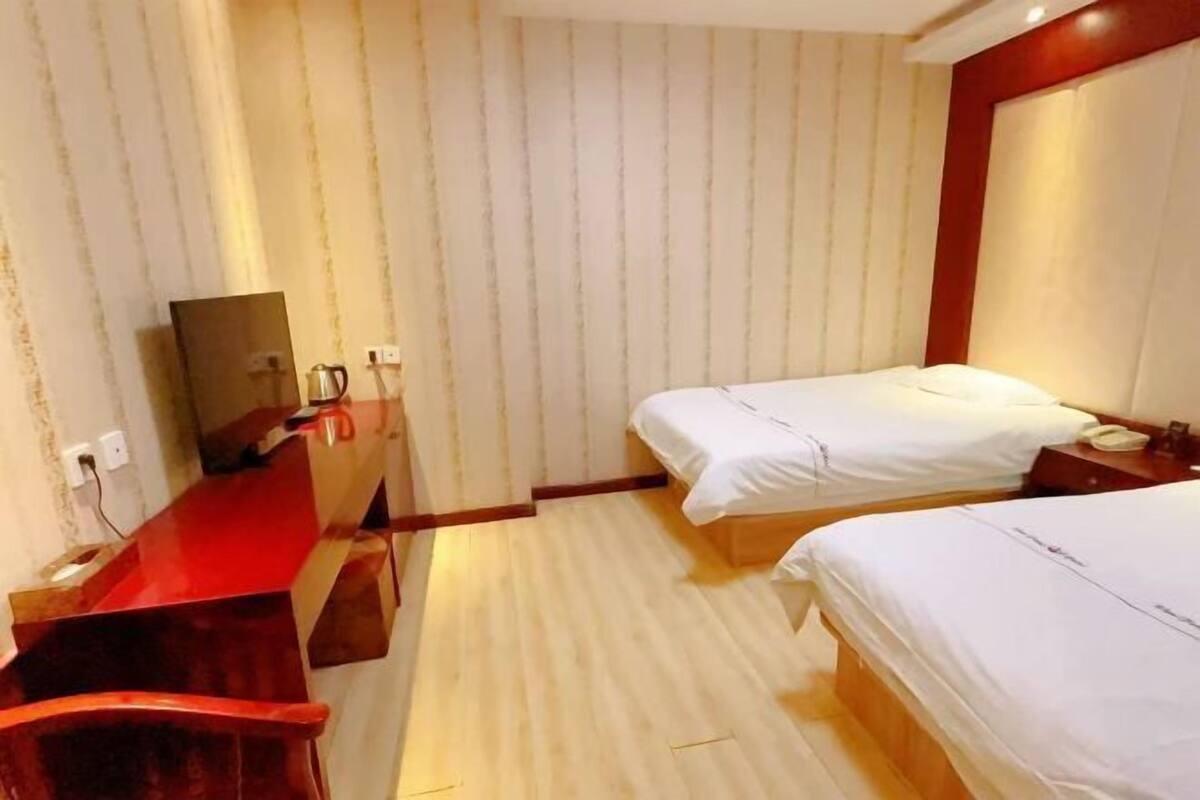 Habitación de hotel con dos camas, un escritorio de madera, un espejo y una pared decorada en rojo.