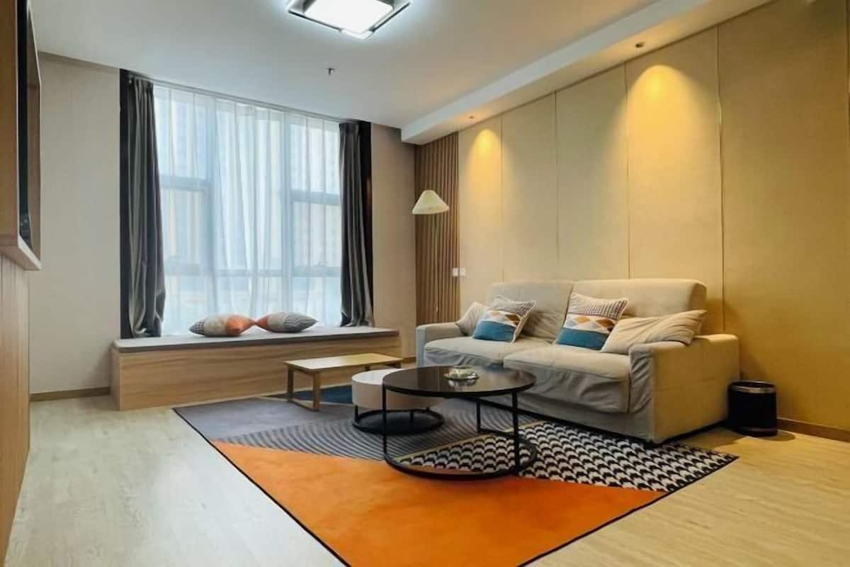 Una sala de estar moderna con un sofá, una mesa de centro y un ventanal con cortinas.