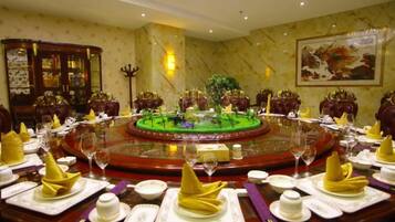 A formal dining room with a round table set for a meal, surrounded by chairs, and a decorative centerpiece.