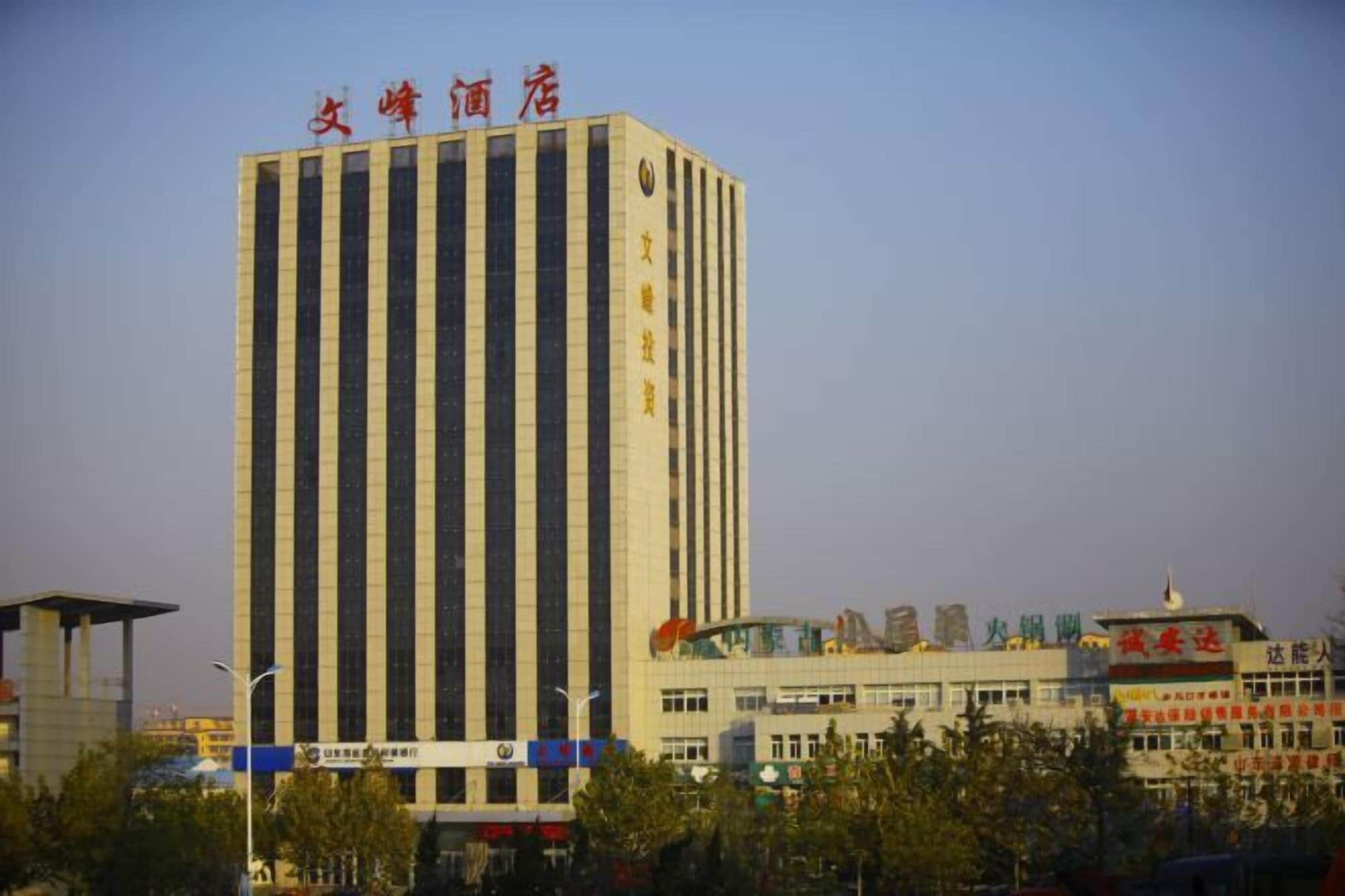 A tall building with vertical lines, a sign with Chinese characters, and a lower structure with a blue stripe.
