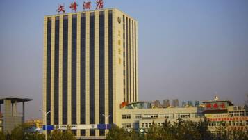 A tall building with vertical lines, a sign with Chinese characters, and a lower structure with a blue stripe.