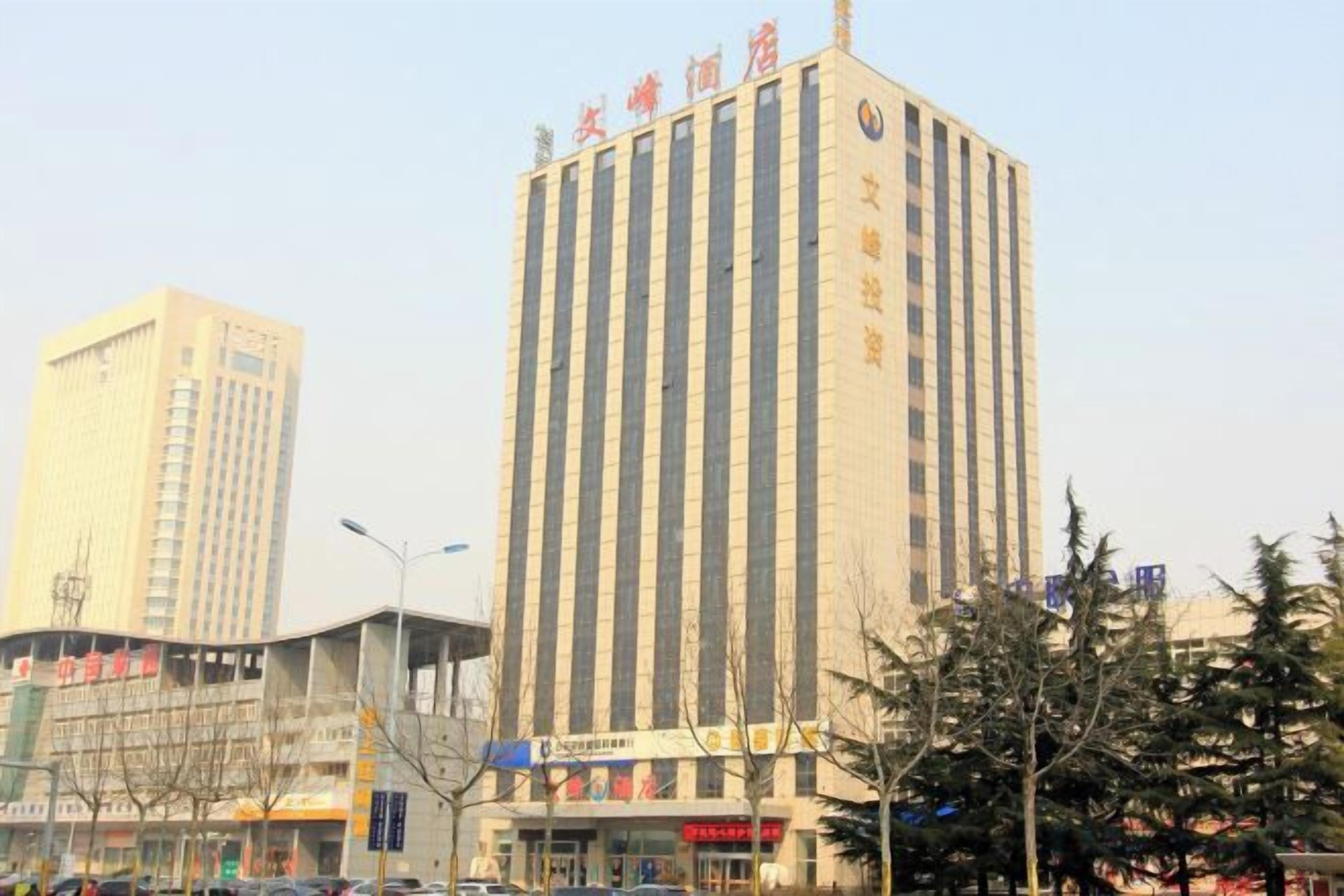 A tall building with vertical lines, a sign with Chinese characters, and a tree in the foreground.