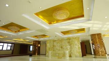 A spacious lobby with a high ceiling, decorative columns, and a marble reception desk.