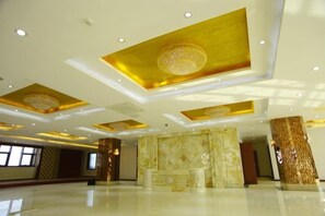 Eine geräumige Lobby mit hoher Decke, dekorativen Säulen und einem Marmor-Rezeptionstresen.