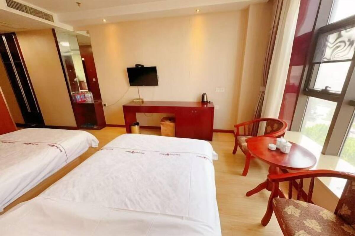Habitación de hotel con dos camas, un escritorio, un televisor y una ventana.