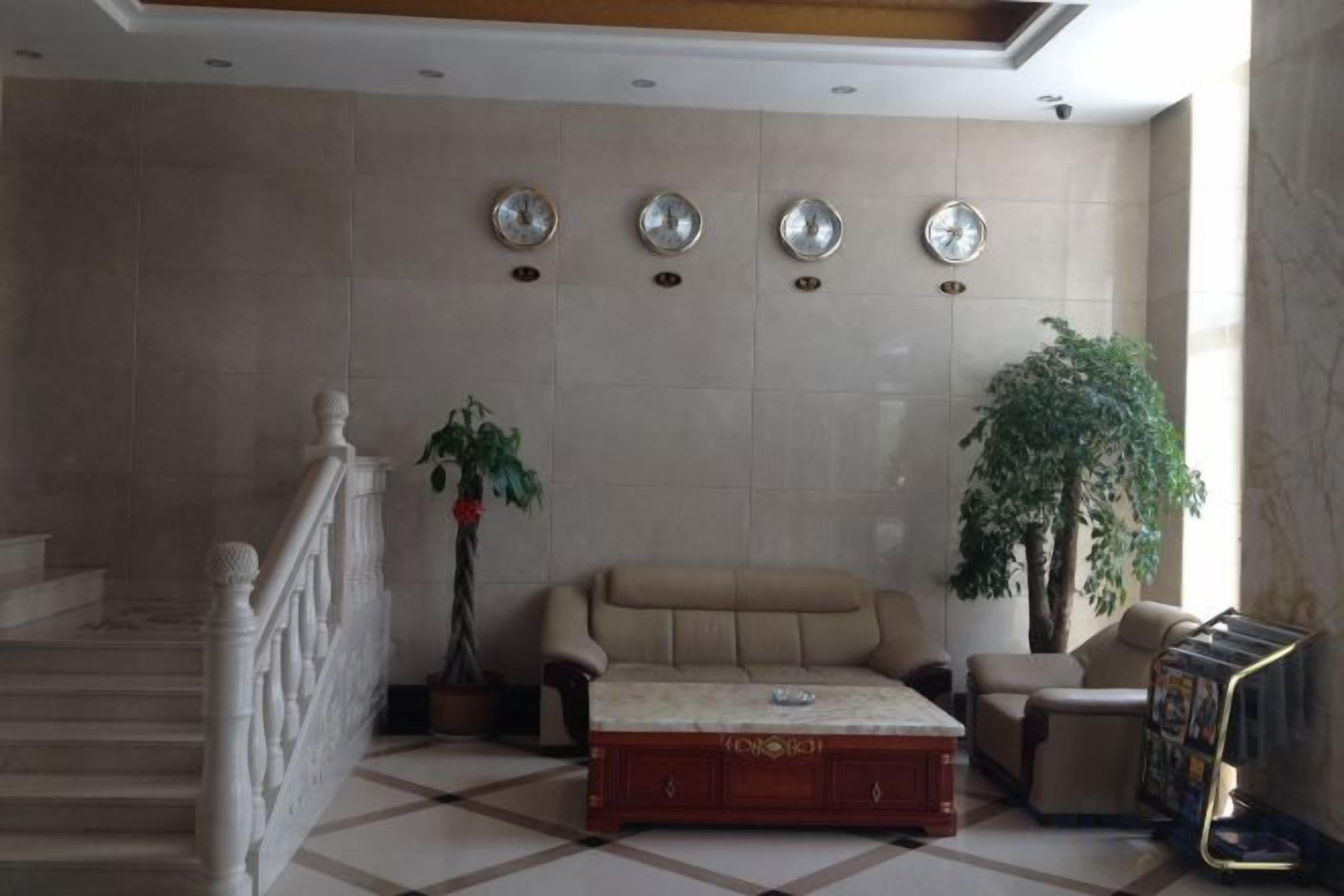 A lobby with a sofa, a coffee table, a staircase, and a large plant.