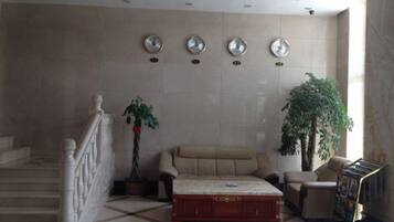 A lobby with a sofa, a coffee table, a staircase, and a large plant.