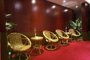 Una habitación con sillas de mimbre, una pequeña mesa, alfombra roja y pared de madera.
