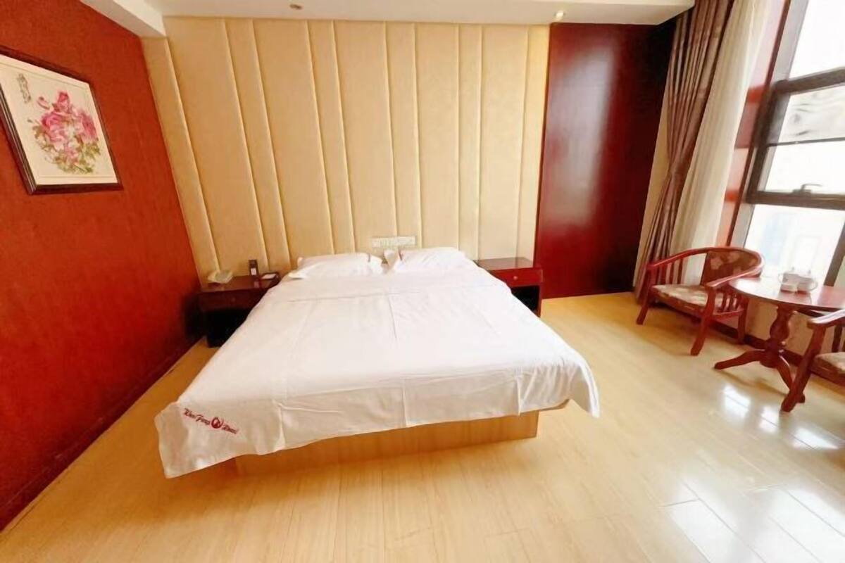Una habitación de hotel con cama, mesita de noche, silla, mesa y ventana.