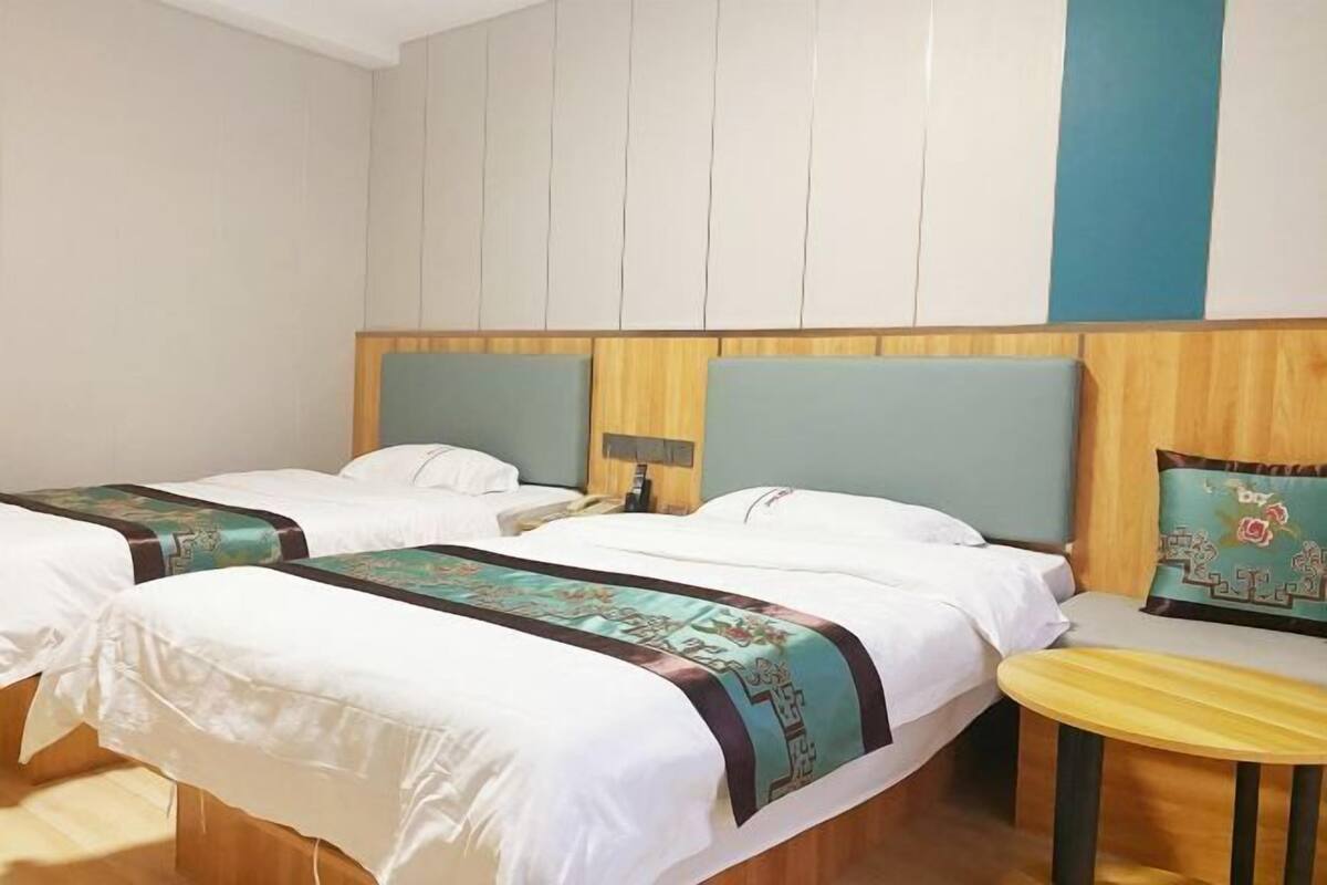 Habitación de hotel con dos camas, una mesita y una mesilla de noche.
