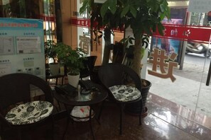 A seating area with tables and chairs, a potted plant, and a sign with Chinese characters. - Jiangyang Business Hotel (Shanghai Jiamusi Road) (Shanghai)