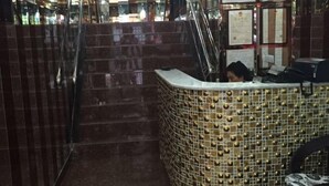 Un área de recepción con un mostrador curvo, una escalera y una pared con diplomas.