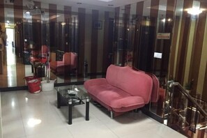 A room with a sofa, a coffee table, and a chair. There is a glass partition and a staircase. - Jiangyang Business Hotel (Shanghai Jiamusi Road) (Shanghai)