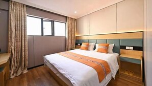 Habitación de hotel con cama, cortinas, un escritorio y vistas al exterior.